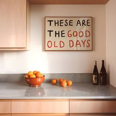 there are oranges on the kitchen counter next to bottles and a sign that says, these are the good old days