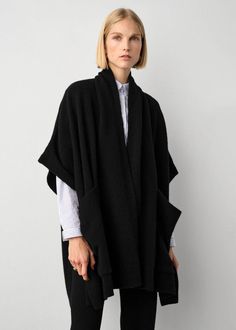 One of the most versatile pieces of the season, this poncho feels like a blanket, but with the fit of an oversized cardigan. The sleeves are loose and fall just over each shoulder, and the style features generous patch pockets that make for the perfect place to warm those fingers on colder days of the year. Throw on over a dress or layer on top a long-sleeve shirt or sweater. This poncho has been designed to fit to a wide range of body types, and is offered in a single size to flatter all. Detai Open Poncho Outfit, Chic Oversized Black Cape, Chic Black Oversized Cape, Chic Oversized Cape With Batwing Sleeve, Black Cape Poncho For Work, Black Workwear Poncho Cape, Oversized Cashmere Cape With Long Sleeves, Black Shawl Cape For Fall, Chic Oversized Outerwear With Batwing Sleeve