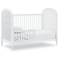 a white crib with a mattress on it