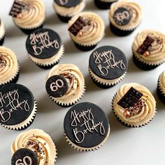 many cupcakes with frosting and decorations are arranged on a white table top