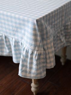 a blue and white checkered tablecloth with ruffled edges on a wooden floor