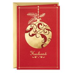 a red and gold christmas card with an ornament hanging from the front, on a white background