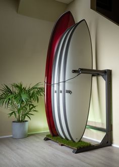 Vertical freestanding surfboard rack shown in a a room next to a green plant with a green flashing light in the background.  The vertical surf rack is flat black in color, has a grass base where the surfboards are.  The rack is holding 4 surfboards. Surf Board Wall Mount, Swimming Pool Area, Surf Rack, Surfboard Rack, Board Rack, Faux Grass, Board Wall, Surf School, Surf Board