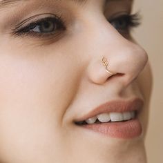 a close up of a woman with a nose ring on her nose and the word love written in gold