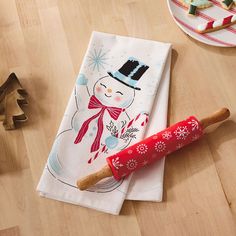 a red rolling pin sitting on top of a wooden table next to a white plate