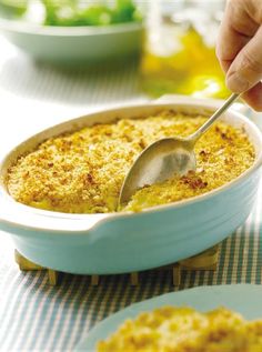 a person is spooning some food out of a casserole dish on a table