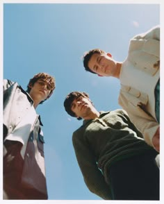 three men standing next to each other looking up at the sky