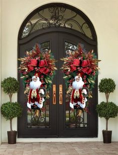 two christmas wreaths on the front door of a house with santa claus and poinsettias