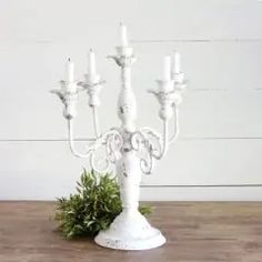 a white candelabra sitting on top of a wooden table next to a potted plant