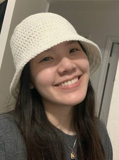 a smiling woman wearing a white crocheted hat