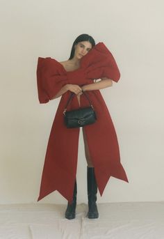 a woman in a red dress holding a black purse