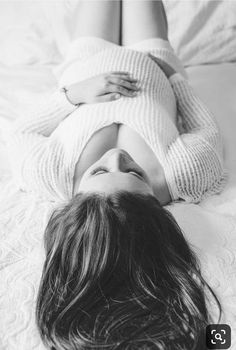 a black and white photo of a woman laying on a bed