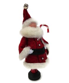 a red and white santa clause doll on a black stand with a bell in it's hand