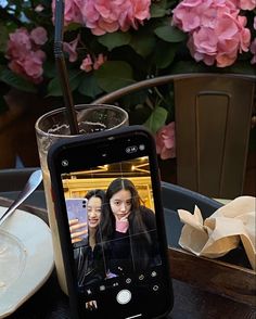 a cell phone sitting on top of a table next to a glass filled with liquid