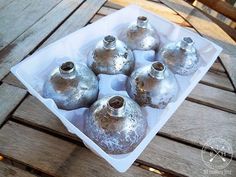 six silver vases sitting on top of a white tray