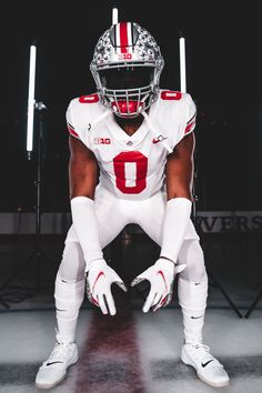 a football player in white and red uniform sitting on the ground with his foot up