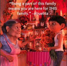 an older woman standing next to a young boy in front of a shrine with candles