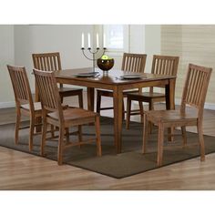 a dining room table and chairs with a rug on the floor in front of it