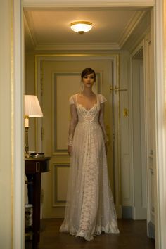 a woman in a white dress is standing in the hallway with her hands on her hips