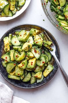 two plates filled with cucumbers and other food