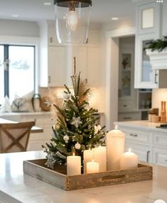 a christmas tree in a tray with candles on the counter next to an open kitchen door