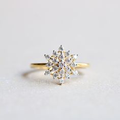 a yellow gold ring with two white diamonds on the front and center, sitting on a light gray surface