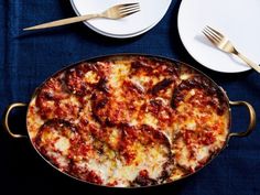 a pizza sitting on top of a pan next to two plates with gold forks and spoons