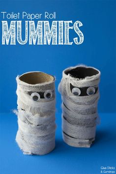 two toilet paper roll mummies sitting on top of each other in front of a blue background