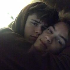 two young men cuddle together in the dark