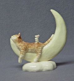 a figurine of a cat sitting on the moon with its tail curled up