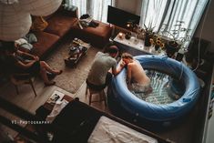 two people are sitting in an inflatable pool while others sit on the floor