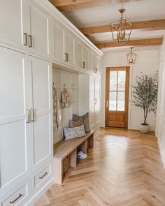 a room with white cabinets and wood flooring next to a wooden entryway door