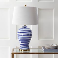 a blue and white striped vase sitting on top of a table next to a lamp