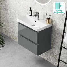 a bathroom sink sitting under a mirror next to a wall mounted towel dispenser