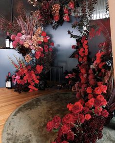 red flowers and greenery are arranged on the wall