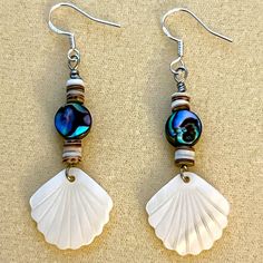 two seashells are hanging from earrings on a table