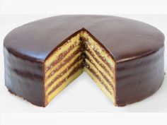 a chocolate and yellow cake with one slice cut out from it's side, on a white surface