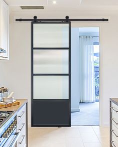 an open door leading to a kitchen with white cabinets and drawers on both sides, in front of a sliding glass door