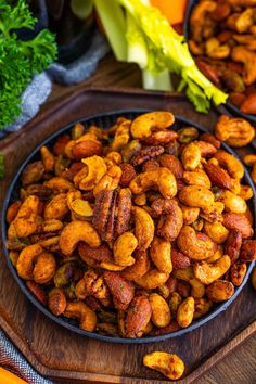 nuts in a bowl on a wooden tray next to carrots and lettuce