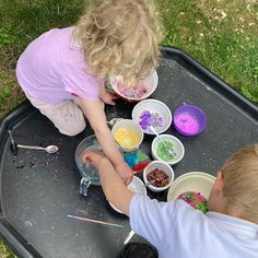 two children are painting with their hands on the tray