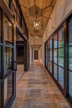 an empty hallway with large windows and wooden ceiling