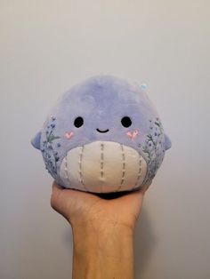 a hand holding a stuffed animal that looks like a whale