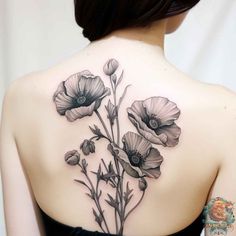 the back of a woman's shoulder with flowers in black and grey ink on it