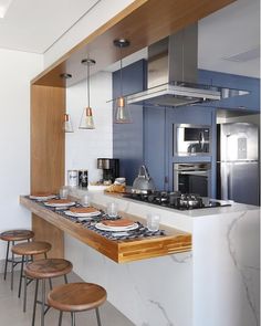 a kitchen with blue cabinets and white countertops, wooden stools and an island