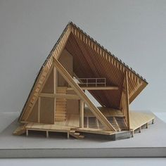 a model of a wooden house on top of a white surface with stairs leading up to the roof