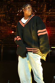 a man standing on top of a stage with his hands in his pockets while wearing a sweater