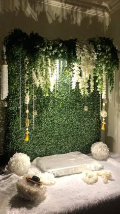 a bed covered in white flowers and greenery next to a wall with hanging lights