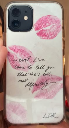 a woman holding up a phone case with lipstick on it