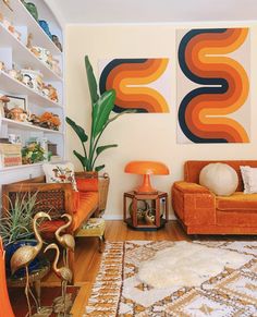 a living room with two orange couches and a large painting on the wall behind them