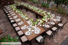 a long table set up with white and green centerpieces for an outdoor event